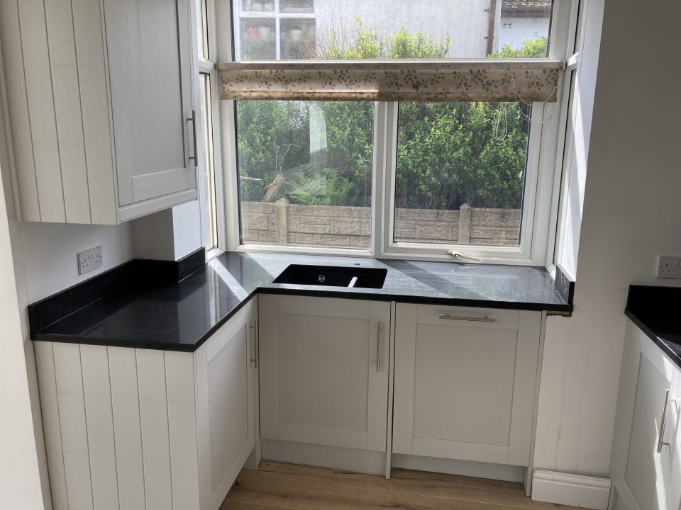 A second view of the finished kitchen — black stone worktops, full-height units and the open-plan space filled with natural light.