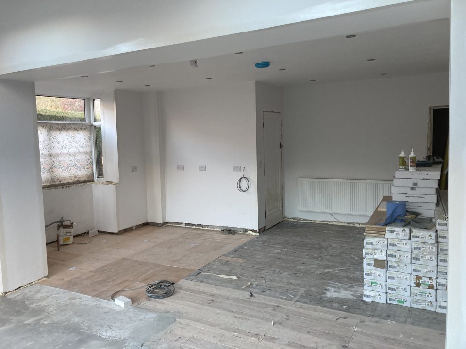 Solid wood flooring laid across the open-plan space, with the kitchen units being set in place.