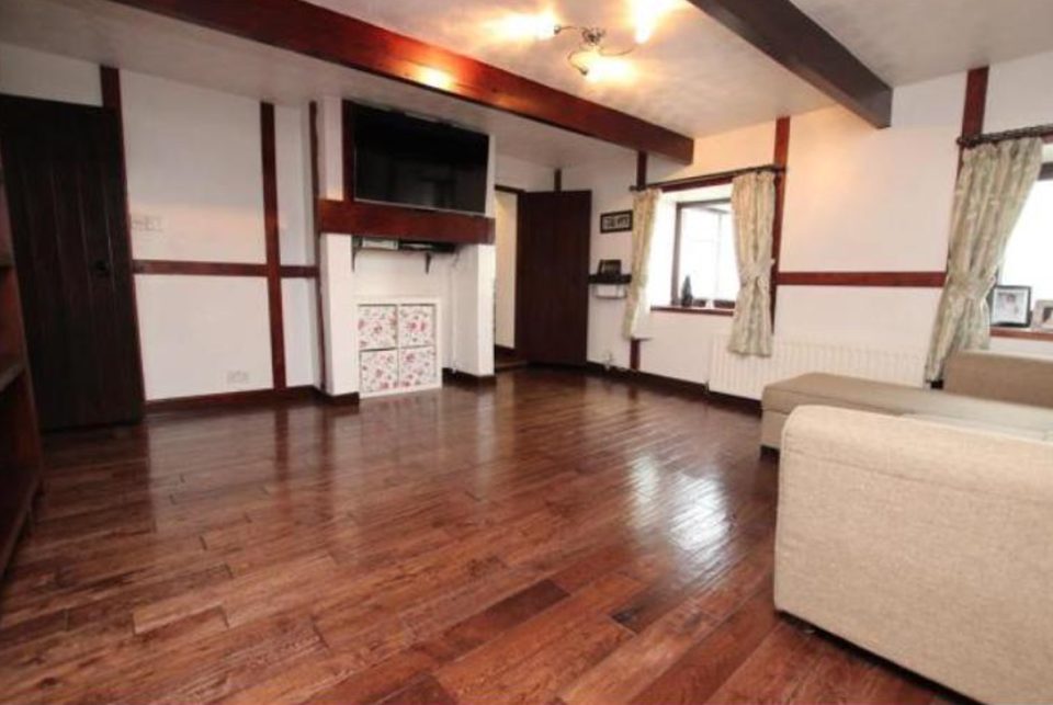 The Blackburn living room before work — dark wood floor, dated fittings and a plain fireplace recess.