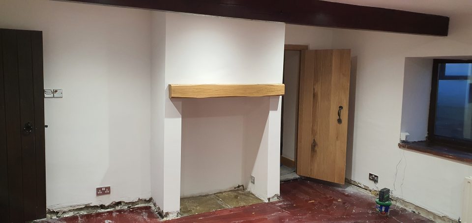 An oak beam mantel being fitted above the fireplace recess.